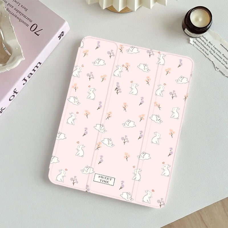 Pink tablet case with bunny and flower pattern on a light gray surface