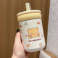 Kawaii bear-themed tumbler with a straw held by a hand against a neutral background