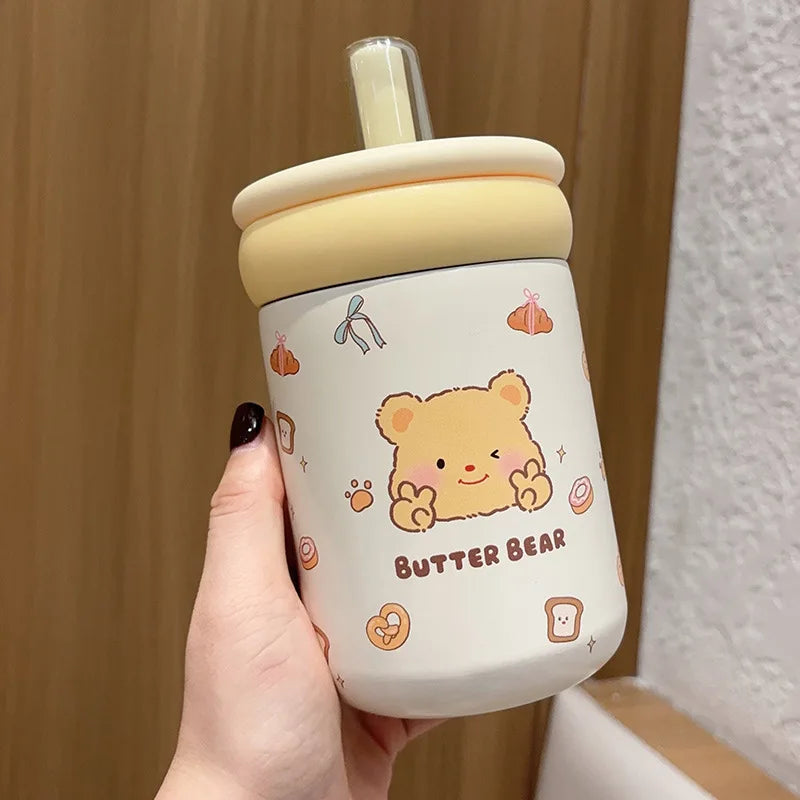 Kawaii bear-themed tumbler with a straw held by a hand against a neutral background