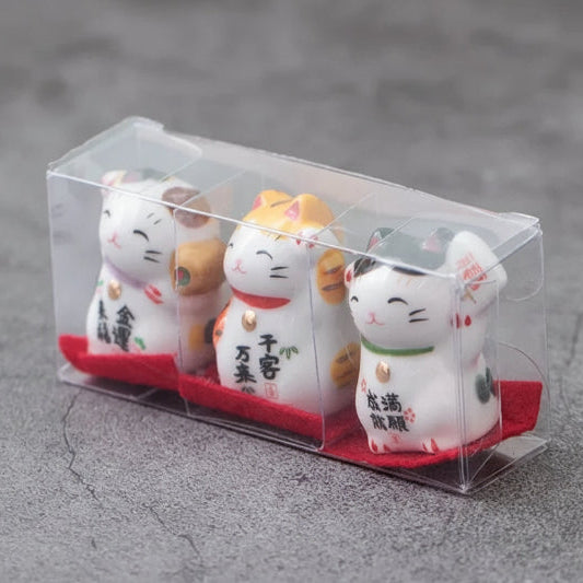 Three small cat figurines in a clear packaging on a gray surface with 'Wontive' branding.