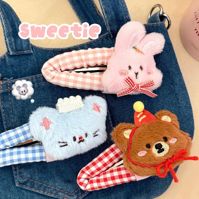 Three cute plush animal-themed hair clips on denim fabric.