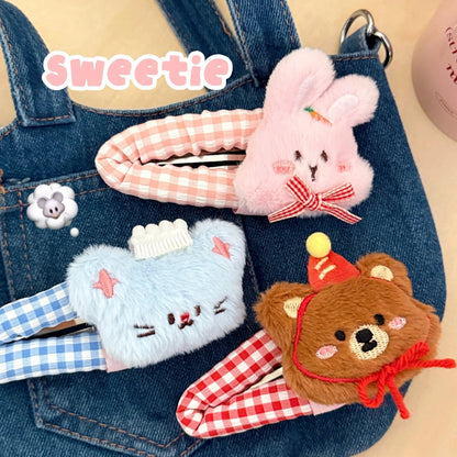 Three cute plush animal-themed hair clips on denim fabric.