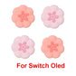 Four pink flower-shaped thumb grips for Switch OLED on a white background
