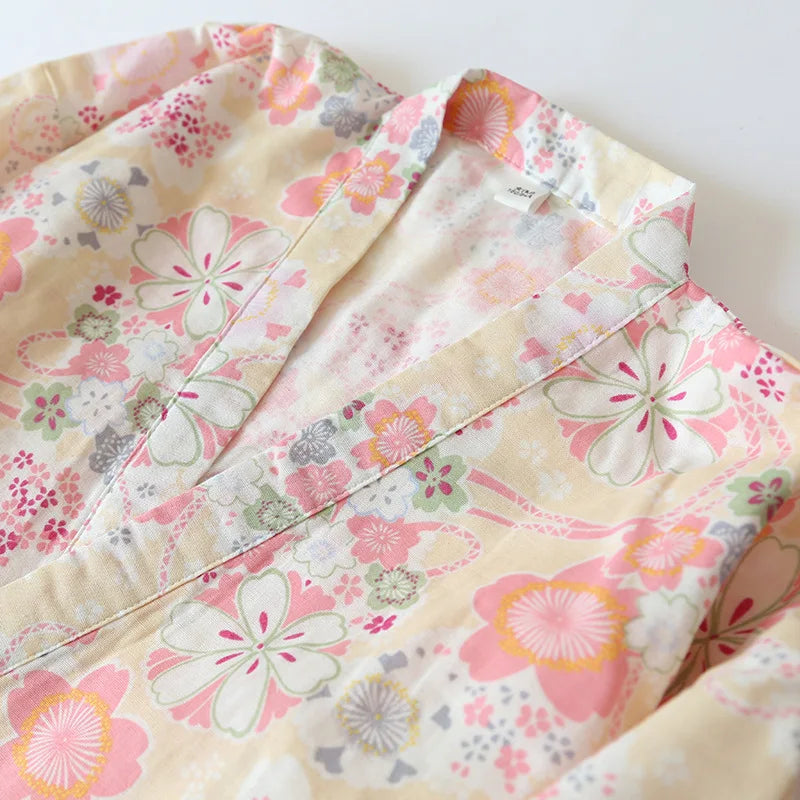 A close-up of a light cream-colored fabric garment, likely a kimono or robe, featuring a delicate floral print in pink, orange, and green.