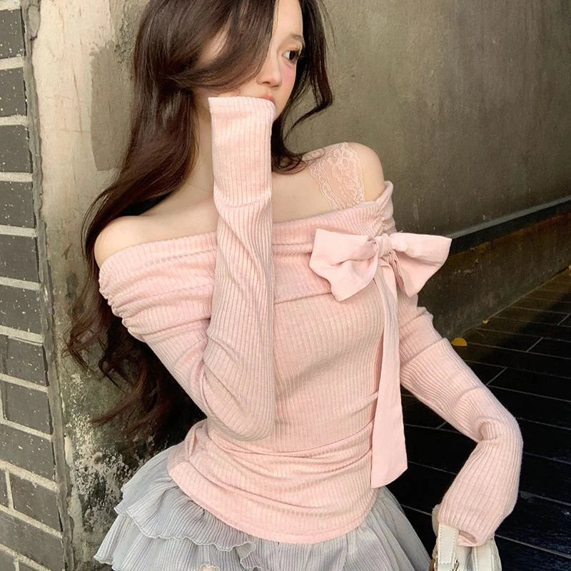 Woman wearing a pink off shoulder shirt with see throuh lace strap on one shoulder and a grey wavy skirt