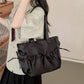 Person holding a black handbag with a bow detail indoors.