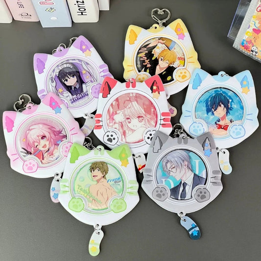 Six anime-themed cat-ear keychain or card holder charms arranged on a dark gray surface. Each charm has a different character illustration and pastel color scheme, including pink, yellow, blue, green, purple, and gray.