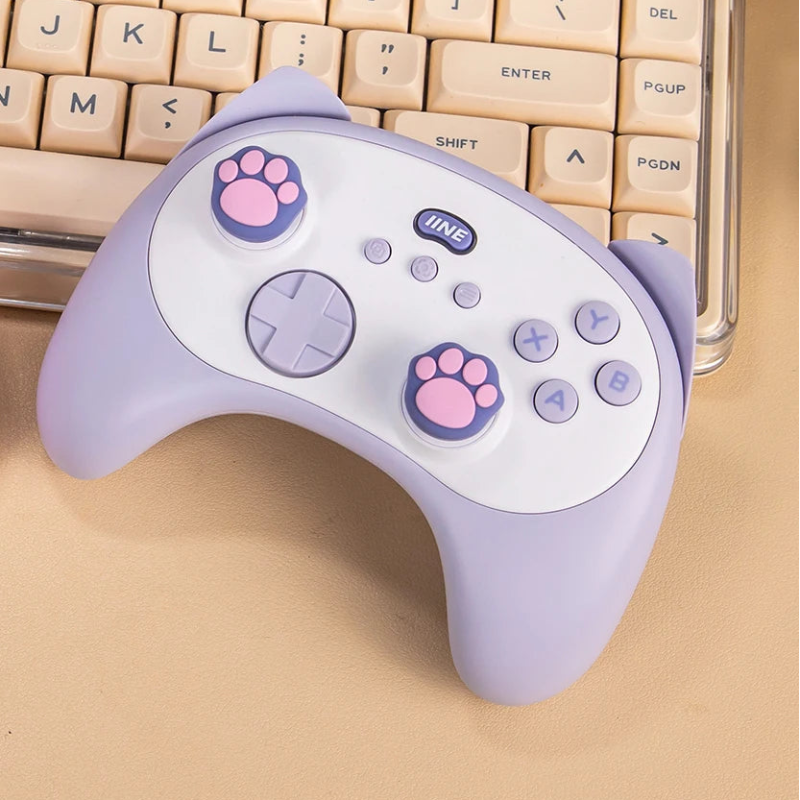 Two pink and purple gaming controllers with paw prints on a beige surface.