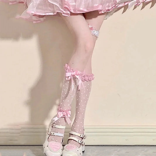 Kawaii front view Polka Dot pink socks modeled by a woman standing against a wall 