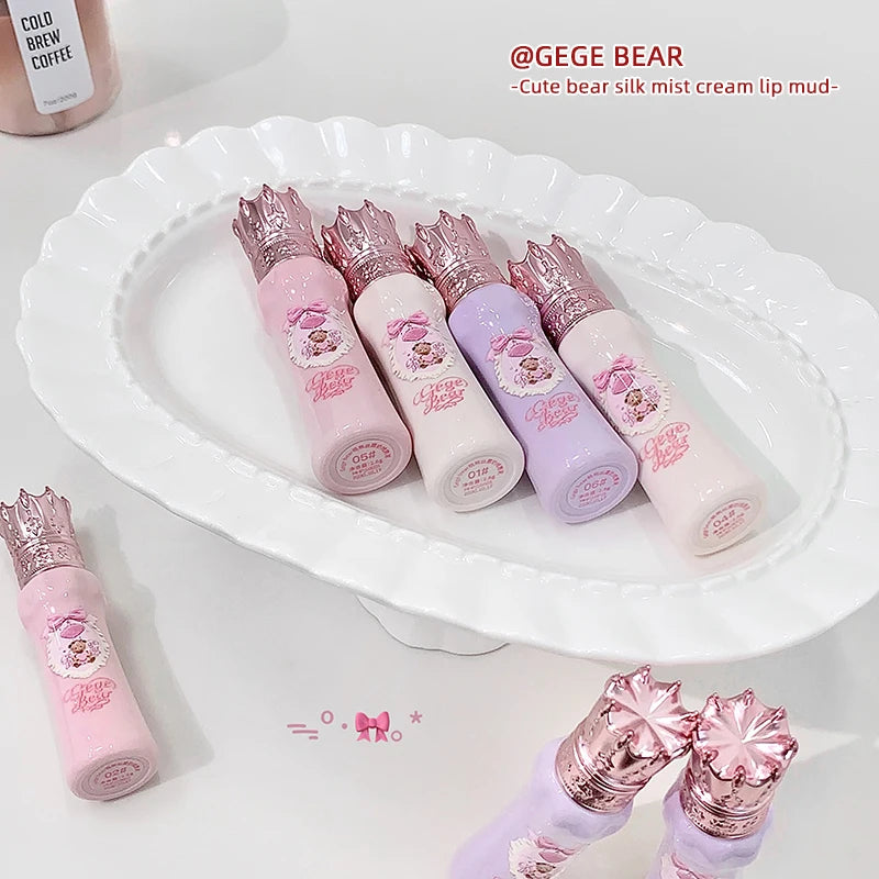 Set of pink and purple lip products with decorative crowns on a white plate, featuring the brand 'GEGE BEAR'.