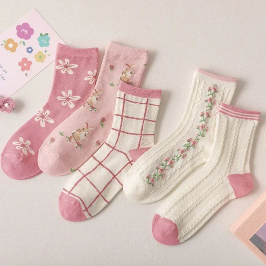 Set of pink and white socks with floral and grid patterns on a light background