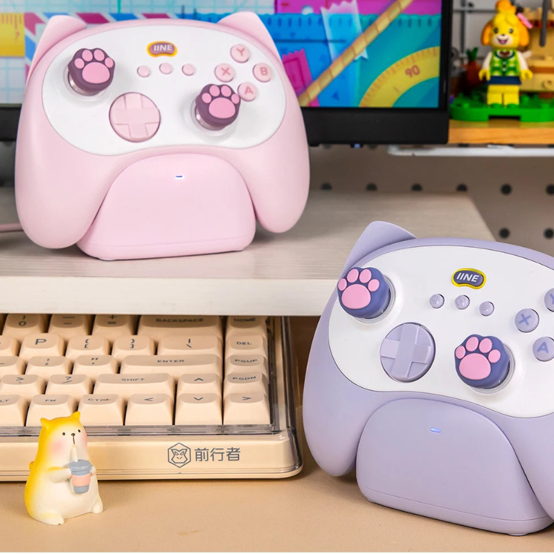 Two cartoon-style gaming controllers on a desk with a computer monitor in the background.