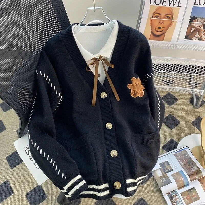 Sweet Teddy Bear Cardigan black edition with a bear sown into the chest area whilst the sleeves have large white stitches where they have been joined and black strips on the wrist cuffs with white, black and white trim.