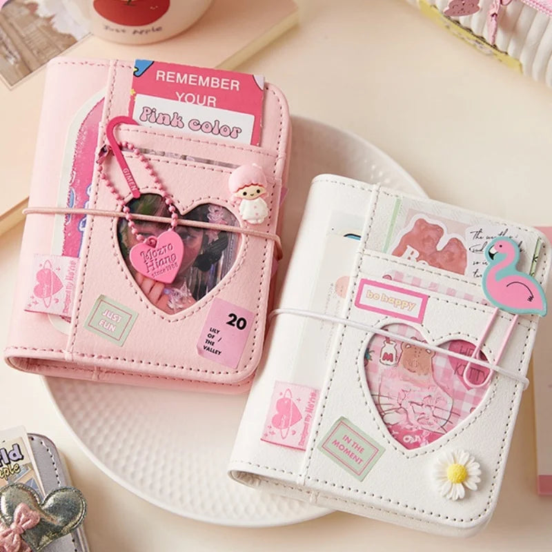 Pink and white mini photo binders with heart-shaped cutout on a plate on a desk.