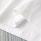 Close-up of white fabric with a textured pattern on a light gray background