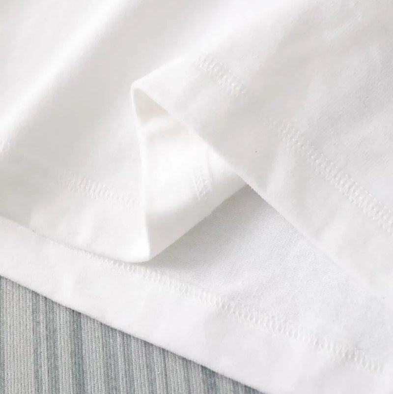 Close-up of white fabric with a textured pattern on a light gray background
