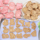 Set of animal-shaped cookie cutters and cookies on a wooden surface