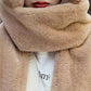 Close-up of a person wearing a beige scarf with a blurred background