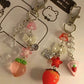 Two colorful keychains with strawberry and heart designs on a white background.