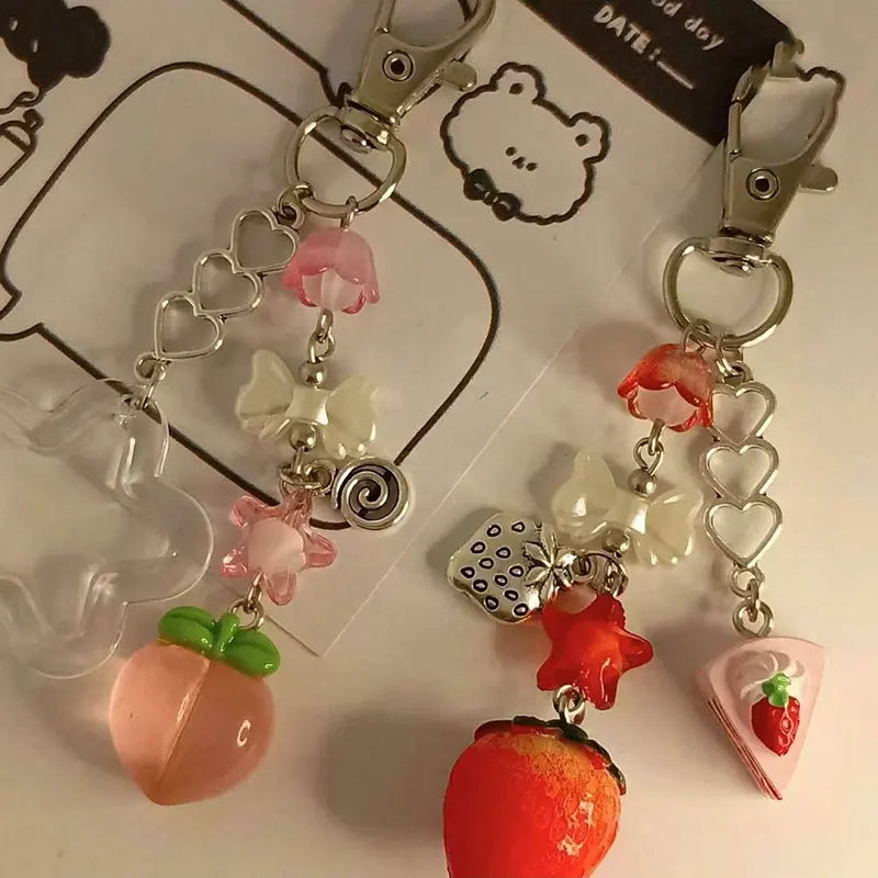 Two colorful keychains with strawberry and heart designs on a white background.