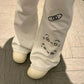 Light grey pants with black designs on a tiled floor