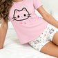 Person wearing pink pajama top with cat design and white shorts with cat pattern on a white background