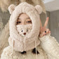 Person wearing a fluffy bear-like hat with a mask, making a peace sign.