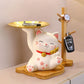 Decorative cat-shaped object with a small table and clock on a neutral background