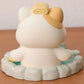 Cute resin figurine of a cat in a onsen with a yellow towel on its head on a wooden surface.
