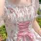 Woman wearing a floral dress with a pink ribbon in an outdoor setting