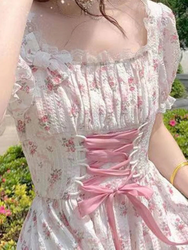 Woman wearing a floral dress with a pink ribbon in an outdoor setting