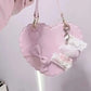 Heart-shaped pink bag with bow and lace details on a light pink background