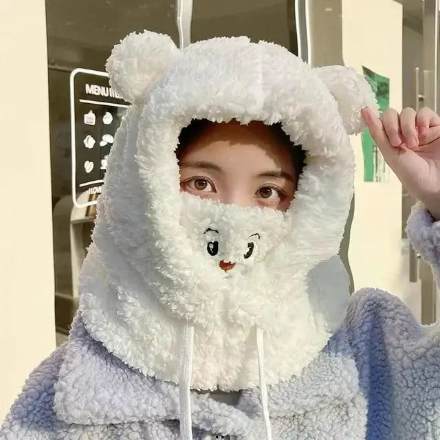 Person wearing a fluffy white hood with kawaii bear design, standing outdoors.