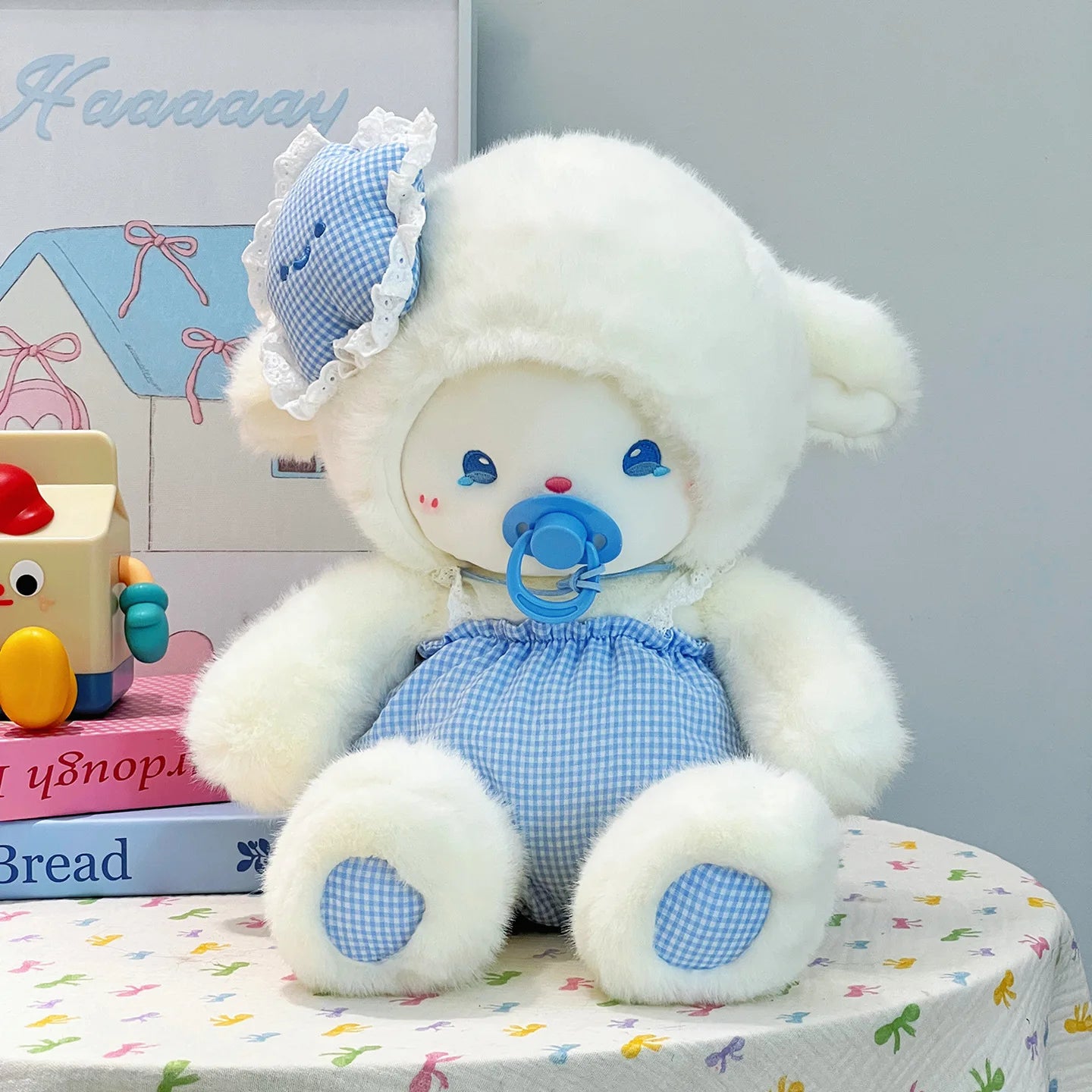 White baby lamb stuffed animal with blue pacifier sitting on a colorful surface.