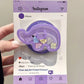a woman holding a kawaii cute elephant quicksand phone grip , this is in the color purple with colorful elephant faces inside on an Instagram background