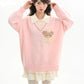 Woman wearing a pink sweater with a teddy bear design and white collar.