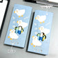 Two light blue boxes of GAGA brand mechanical pencil lead sets, featuring cartoon duck illustrations and a die-cut window showing the blue and yellow pencil leads inside. The boxes are placed on a gray desk next to a pen.
