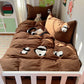 A children's bed dressed in a brown bedding set with embroidered panda motifs, shown in a styled bedroom setting with a white crib, toys, and wall decorations.