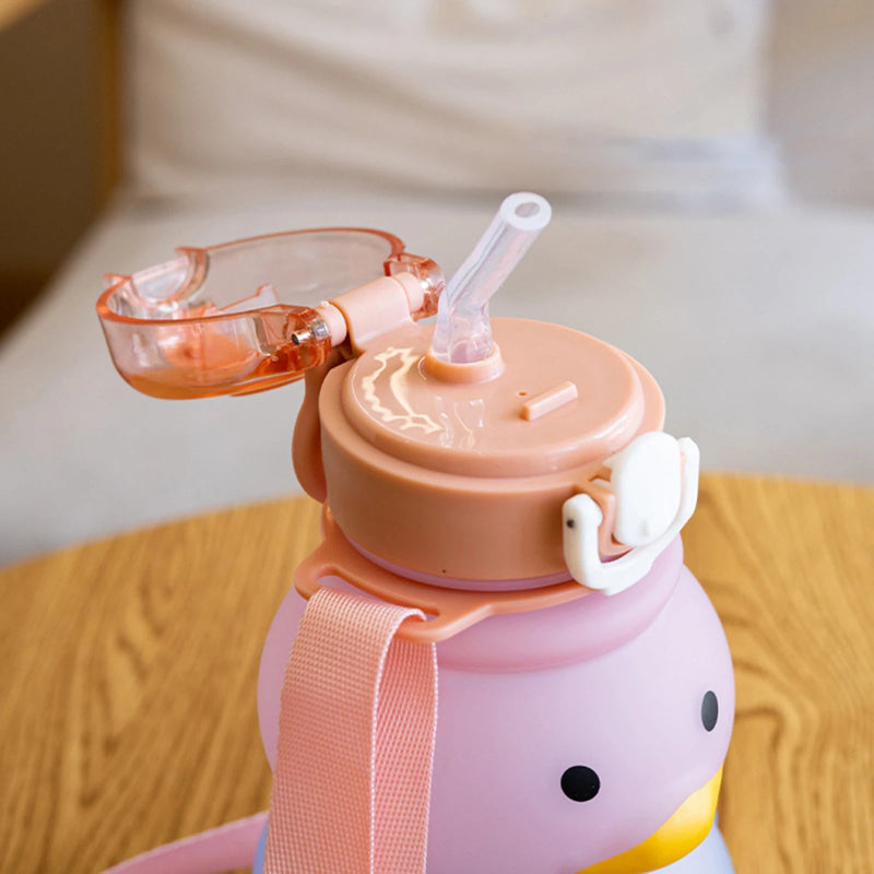Pink children's water bottle with a straw lid on a wooden surface