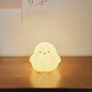 Cute chick-shaped night light on a wooden surface with a soft glow.