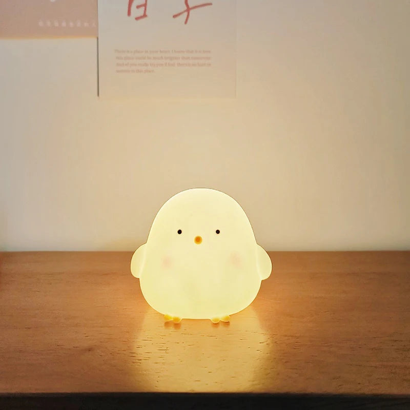Cute chick-shaped night light on a wooden surface with a soft glow.