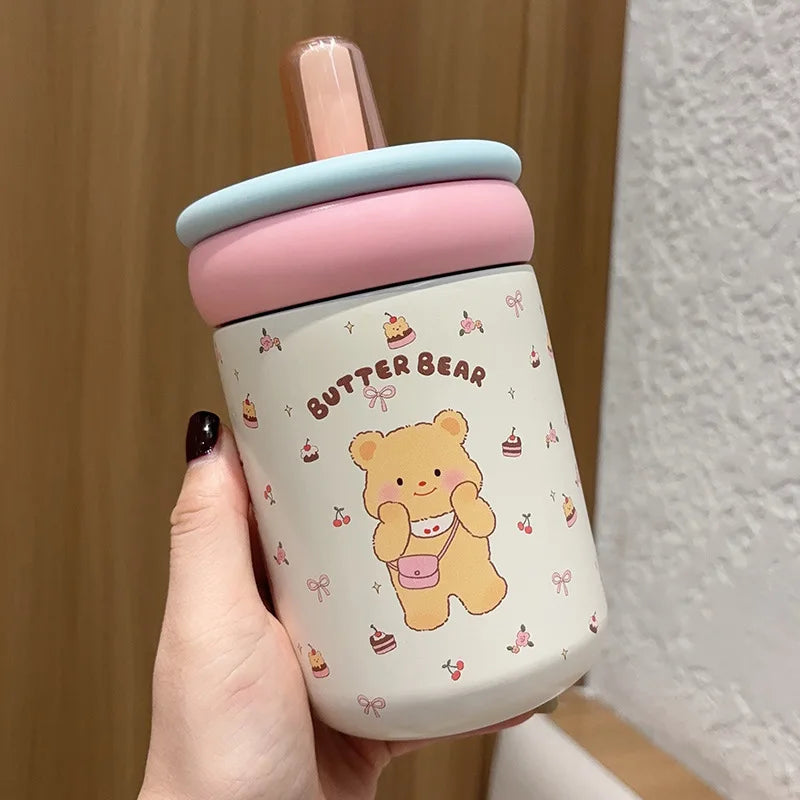 Pink sippy cup with 'Butter Bear' design held by a hand against a neutral background