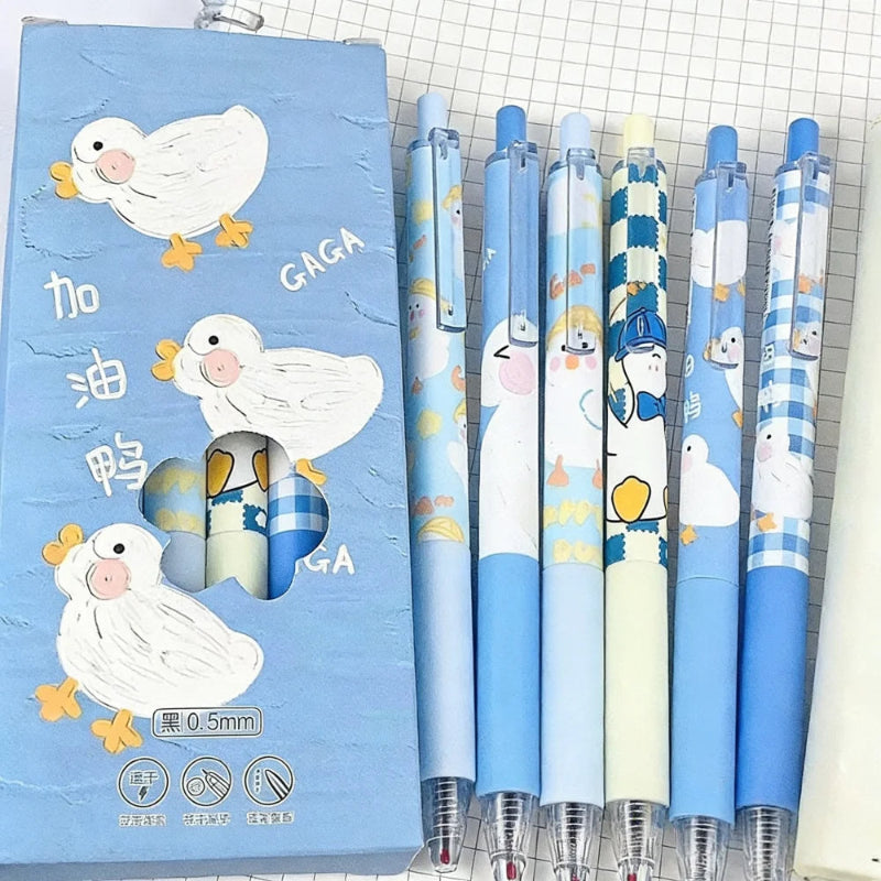A set of five cartoon duck-themed retractable gel pens displayed next to their blue packaging box on a white grid paper background.