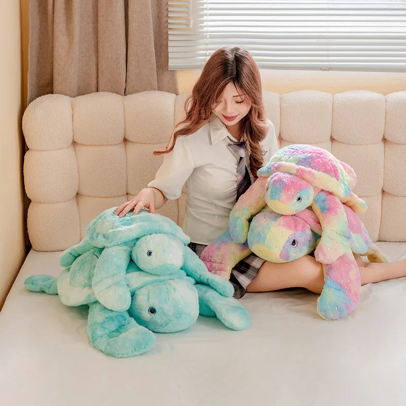 Plush blue and pastel turtles being held by a woman on a sofa