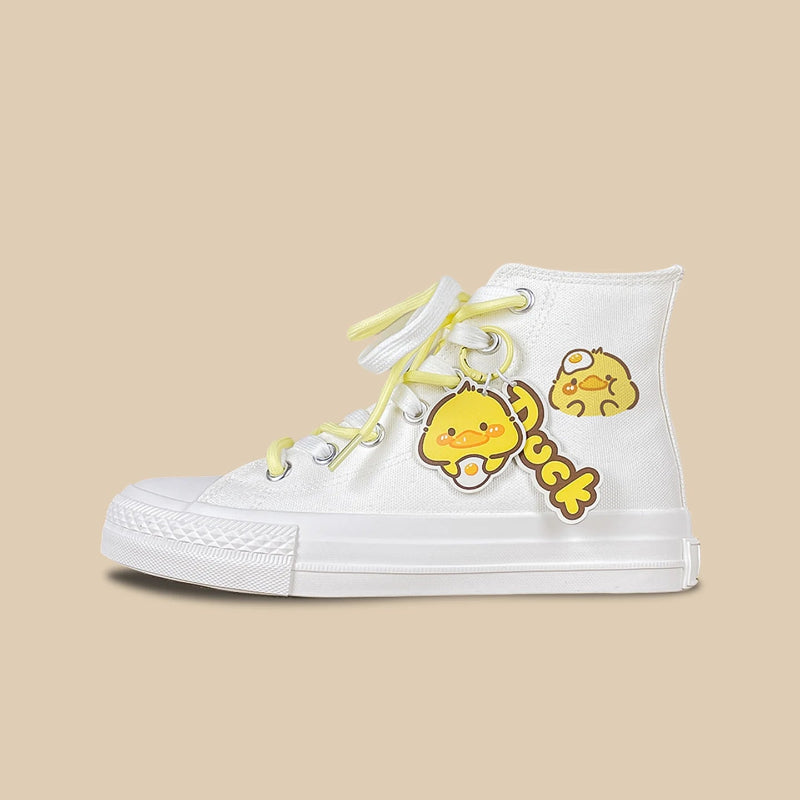 A white high-top canvas sneaker featuring a cute yellow duck character charm and matching yellow laces, set against a solid beige background.