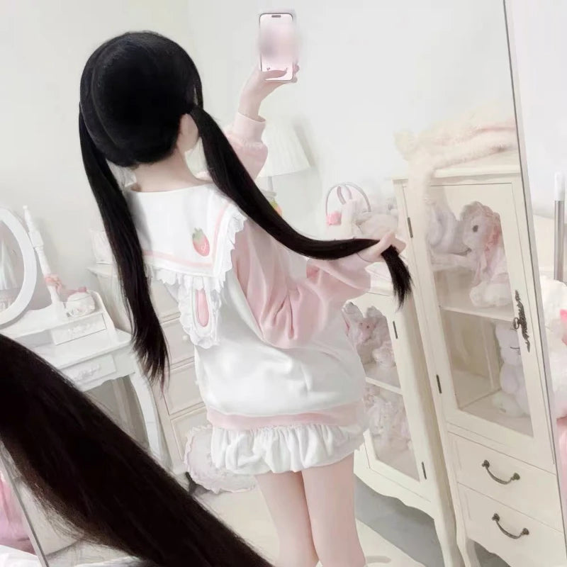 Person wearing a white and pink outfit with long black hair in a room.