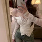 Person wearing a white lace top and jeans taking a mirror selfie.