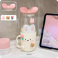 Kawaii pink toothbrush holder with bunny ears, displayed on a gray surface.