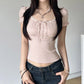 Woman wearing a pink top with puffed sleeves and dark jeans against a plain background
