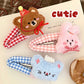 Three kawaii plush animal hair clips with checkered patterns on a book page.